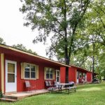Red cabins with outdoor seating and grills surrounded by trees at Foxfire Resort Cabins on Table Rock Lake