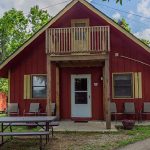 Red cabin with balcony and picnic table surrounded by trees at Foxfire Resort Cabins on Table Rock Lake